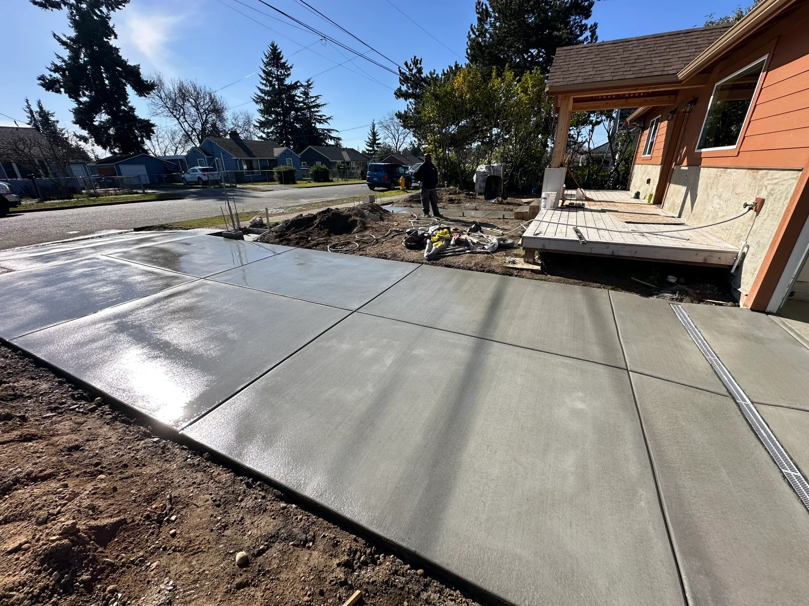 Newly poured concrete patio with control joints and broom finish texture next to residential home