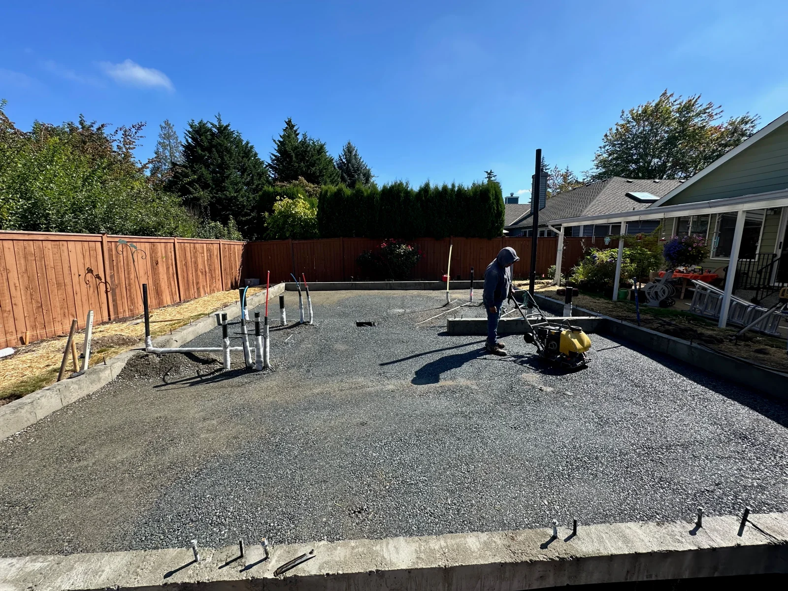 Finished concrete pad with aggregate surface, steel edging, and reinforcement in residential backyard