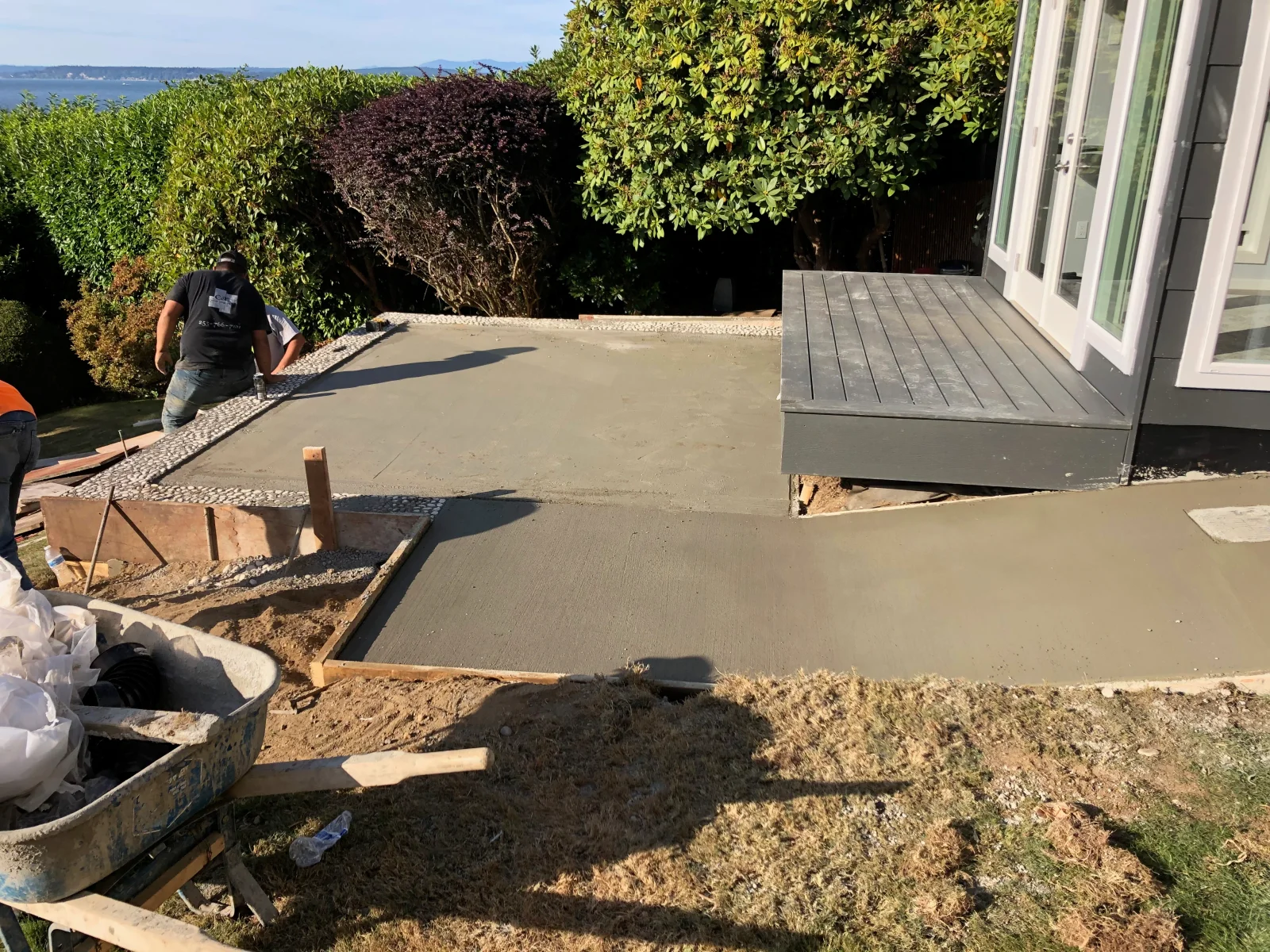 Concrete patio and walkway pour in progress with finishing work and gravel borders