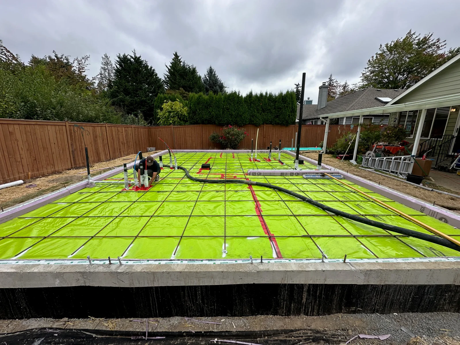 Radiant heating tubing grid on concrete pad with color-coded PEX lines and concrete framing