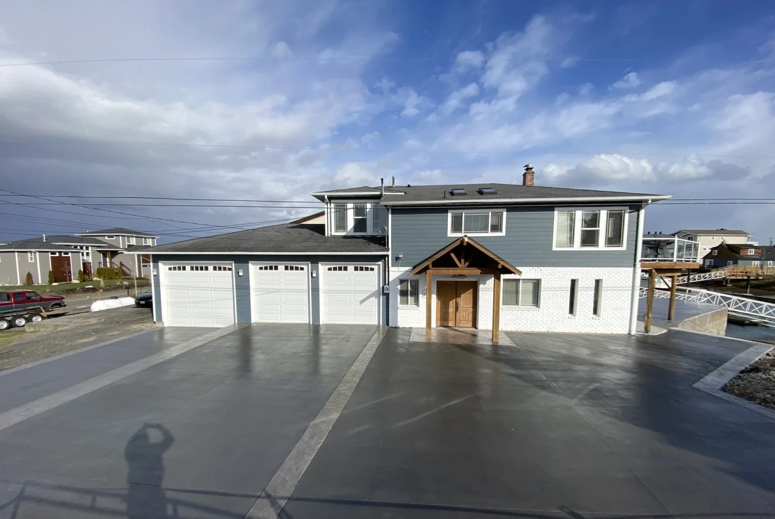 Finished concrete driveway and apron with three-car garage and wooden entry pergola