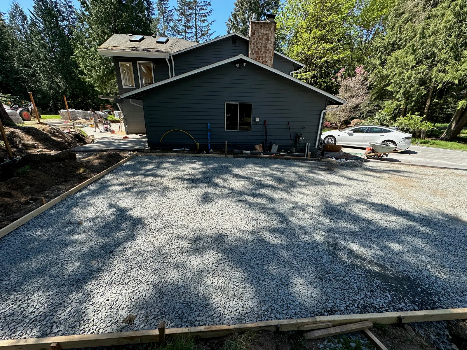 Compacted gravel driveway base with timber edging and wood-framed house
