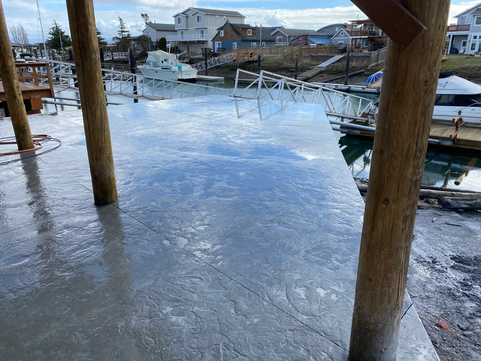 Stamped concrete patio with Roman slate finish at waterfront marina, wooden pilings visible