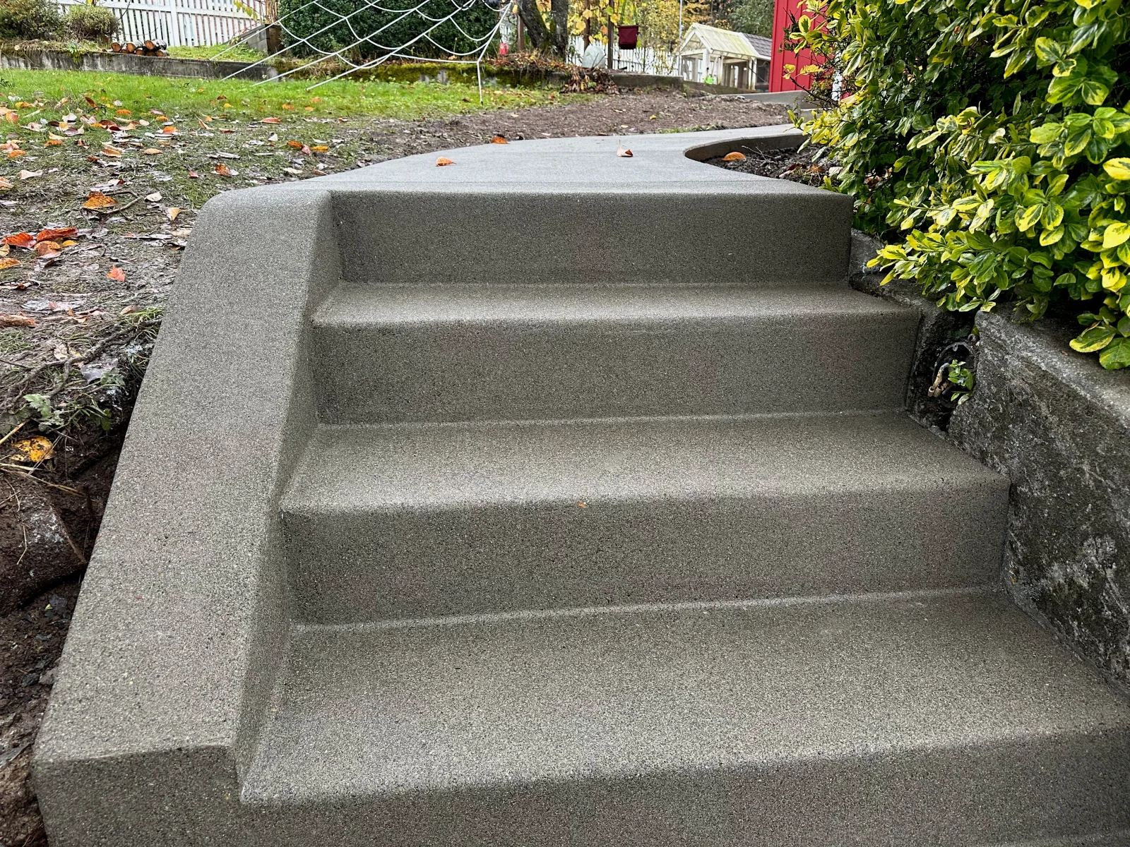 Finished concrete steps with smooth gray surface and curved design in backyard setting